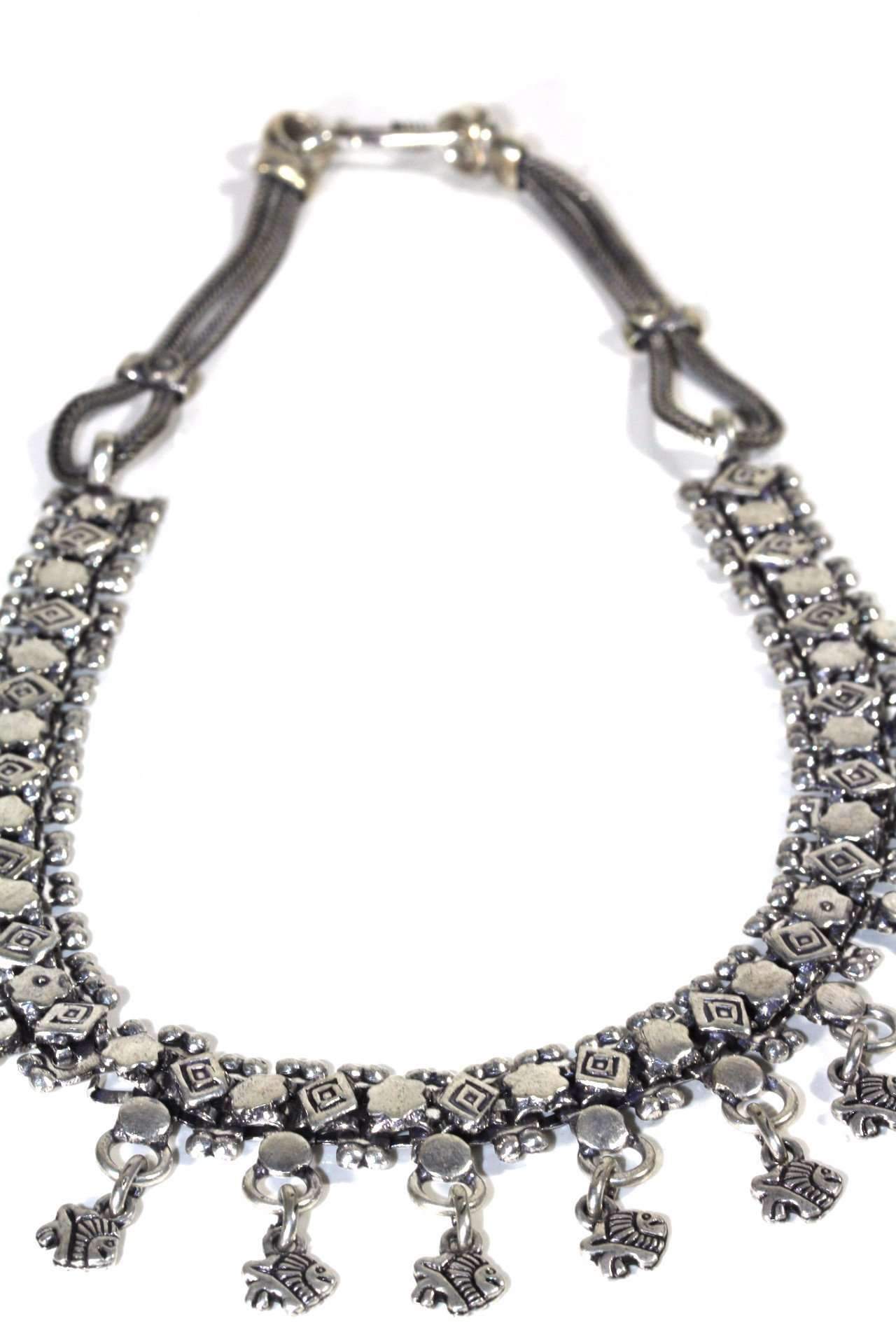 The Fish Charms Tribal Choker Necklace is a handmade silver piece with intricate geometric patterns and dangling charms, elegantly displayed against a white backdrop—a true tribute to tribal necklace artistry.