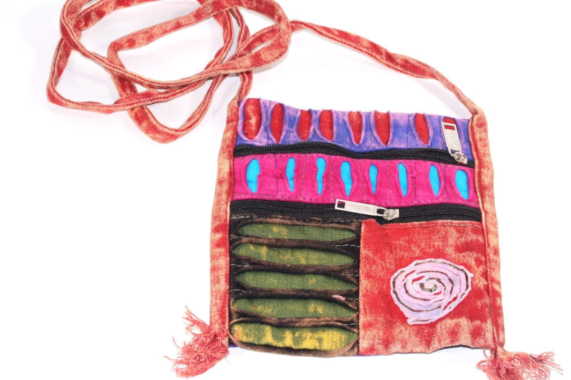 The Spiral Cross Body Patchwork Passport Bag features a vibrant hippie style with red, purple, blue, and green patterns. Handmade from cotton, it comes with multiple zippers and an adjustable strap, adorned with a charming flower design on the lower right corner.