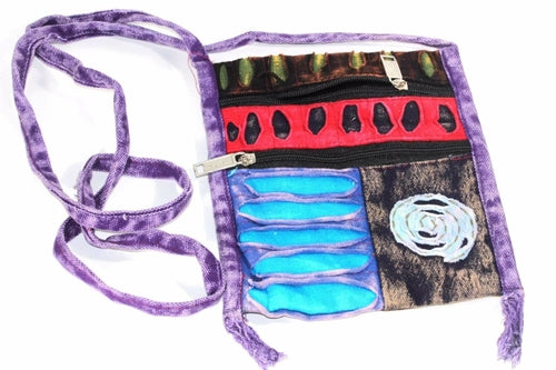 The Spiral Cross Body Patchwork Passport Bag features a vibrant hippie style with red, purple, blue, and green patterns. Handmade from cotton, it comes with multiple zippers and an adjustable strap, adorned with a charming flower design on the lower right corner.