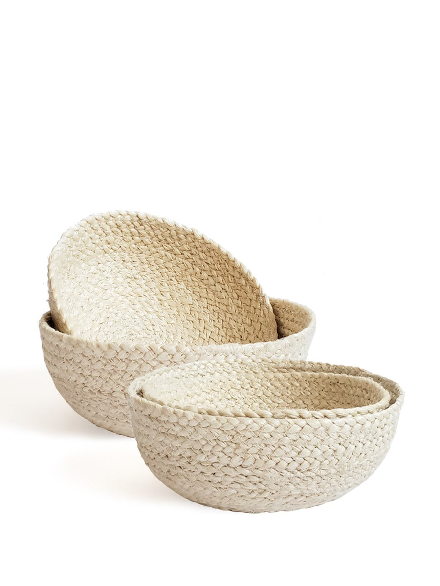 On a flat surface against a plain background, a set of four Kata Candy Bowls in white, crafted by fair trade artisans, is displayed. These versatile woven straw baskets highlight the beauty and authenticity of natural jute.