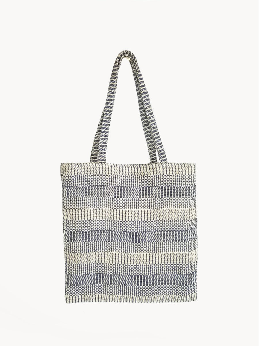 The Dobi Daily Bag - Blue is a tote bag crafted from handwoven jute-cotton fabric by Fair Trade artisans, featuring two handles set against a plain background, with gray and white horizontal stripes.