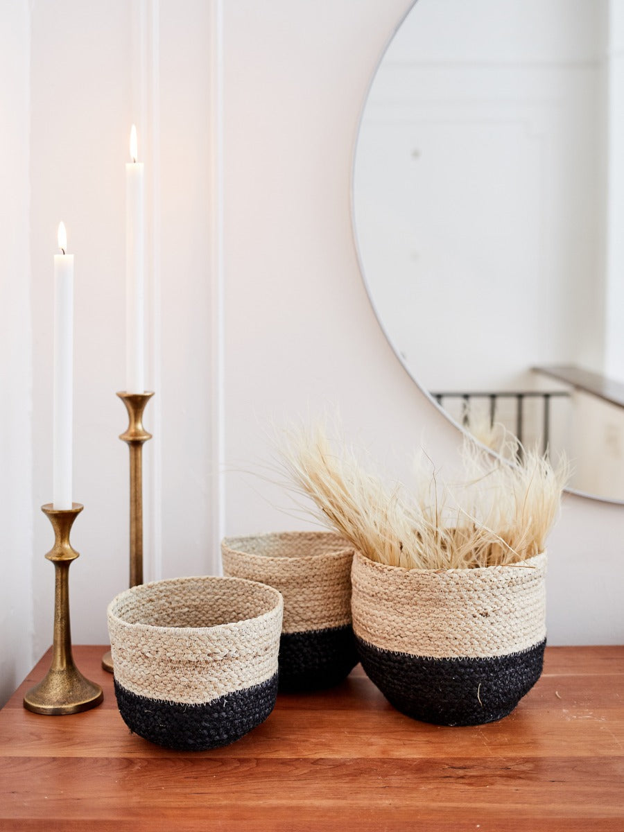 Three Naiya Bin baskets, handwoven by Fair Trade artisans with varying sizes and featuring natural upper halves and black lower halves, are arranged side by side against a light background.