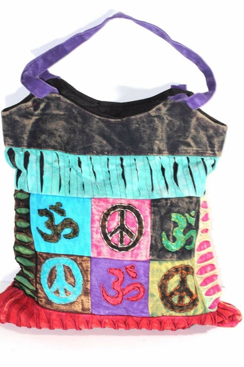The Peace & Om Patchwork Jhola Carry Bag, featuring green handles, presents spiritual symbols like peace and Om in multicolored embroidered squares through its vibrant handmade design.