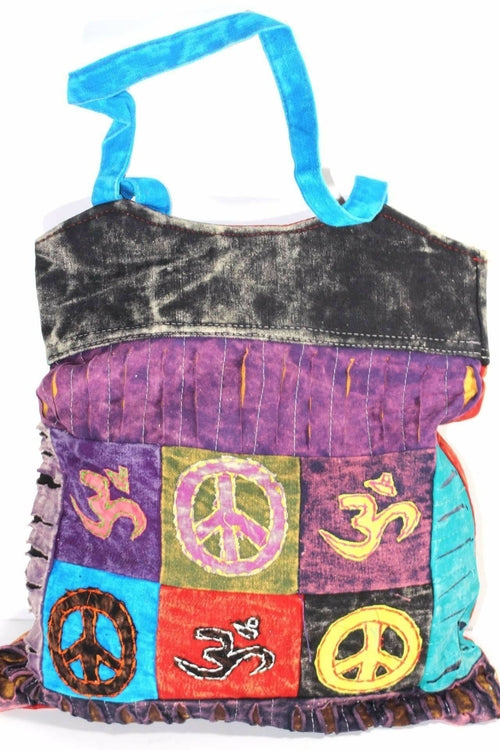 The Peace & Om Patchwork Jhola Carry Bag, featuring green handles, presents spiritual symbols like peace and Om in multicolored embroidered squares through its vibrant handmade design.