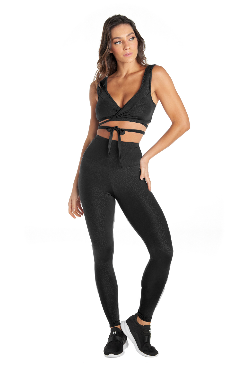 A person wears Black Dream High Waisted Leggings with tummy control and sweat-wicking features, standing against a white background. The lower half is shown, matched with sleek black sneakers.