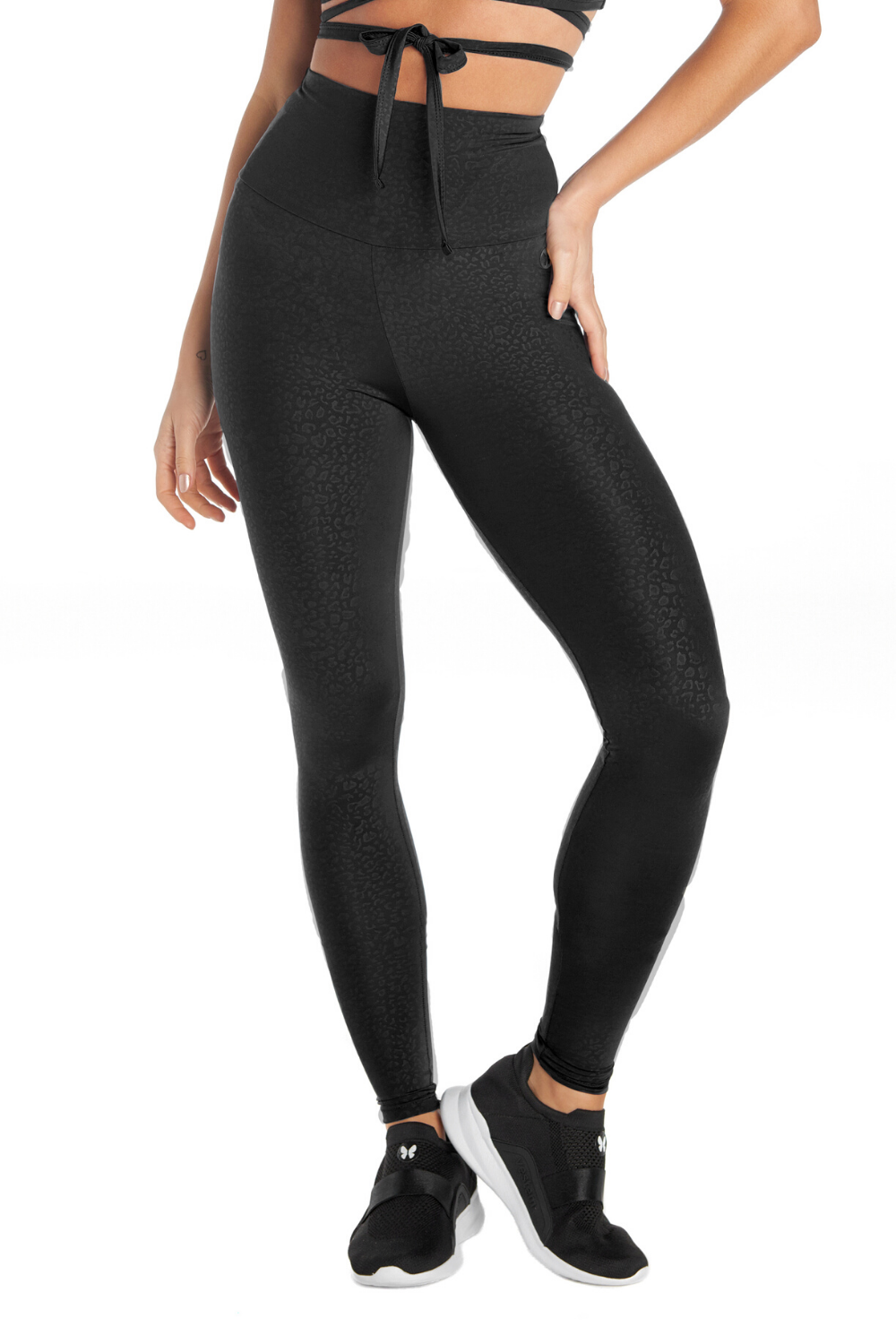 A person wears Black Dream High Waisted Leggings with tummy control and sweat-wicking features, standing against a white background. The lower half is shown, matched with sleek black sneakers.