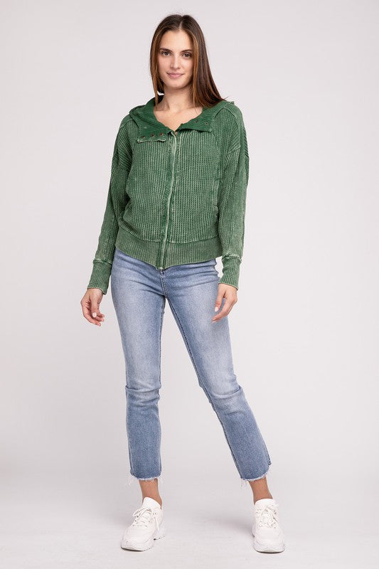 Woman in a Acid Wash Cotton Waffle Hooded Zip-Up Jacket with pockets and black pants, smiling and posing with hands on hips, against a light gray background.