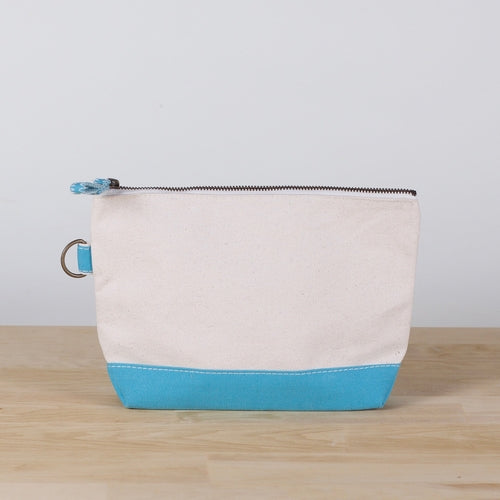 A small heavyweight canvas pouch with a black bottom, featuring a sturdy metal zipper and side loop detail, from the All In Zip Top Pouch collection.