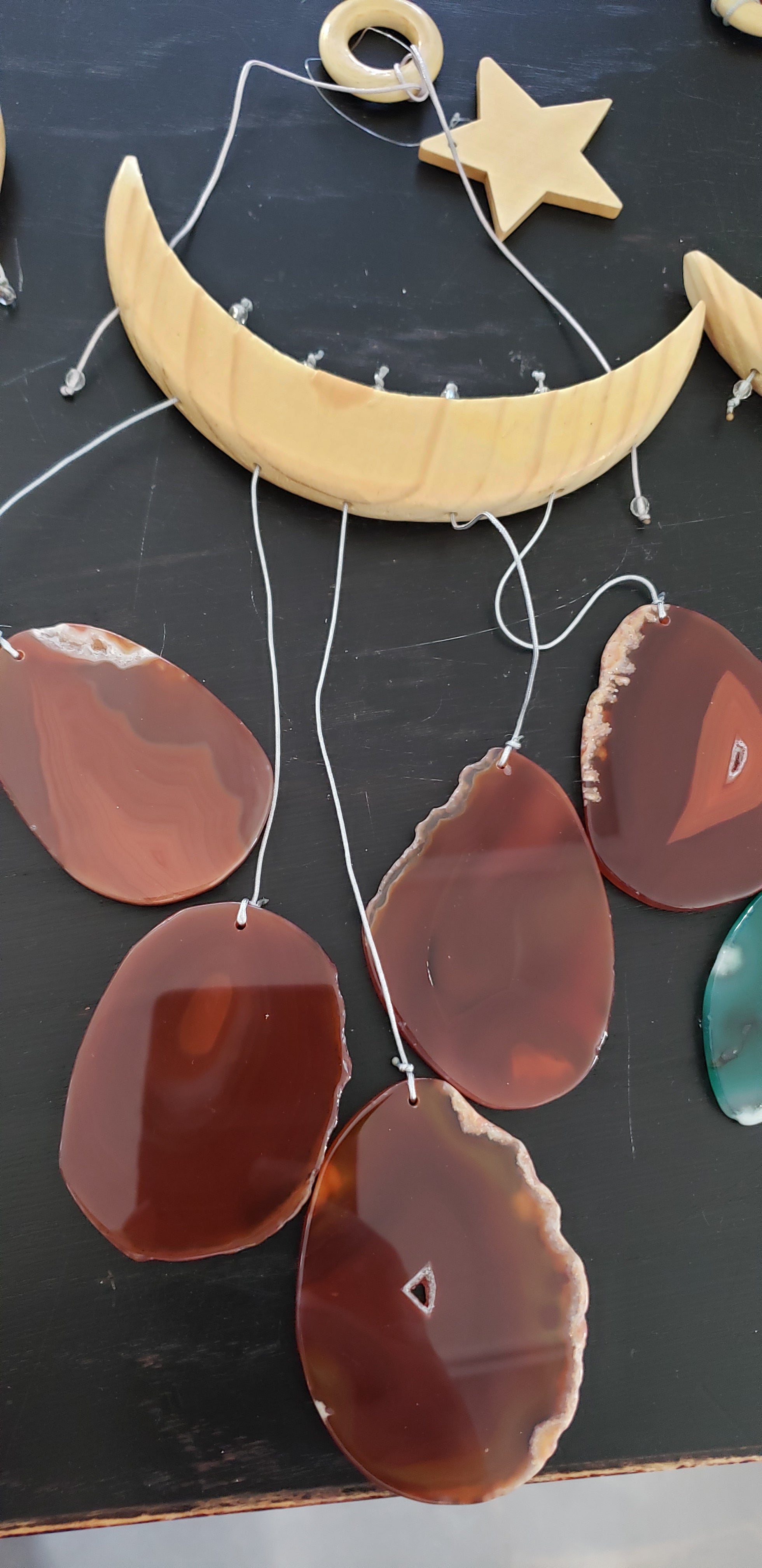 The NEW Star & Crescent Moon Agate Wind Chime features a mesmerizing wood crescent moon embellished with vibrant stones that mimic natural agate slices, all elegantly accentuated by two wooden triangular shelves.