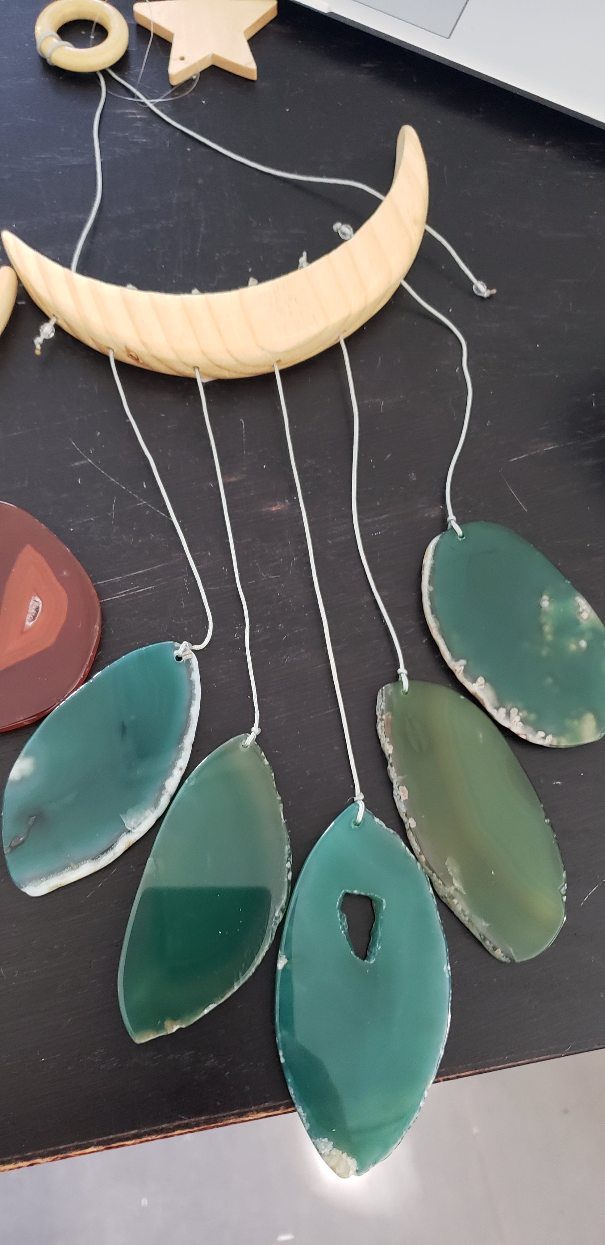 The NEW Star & Crescent Moon Agate Wind Chime features a mesmerizing wood crescent moon embellished with vibrant stones that mimic natural agate slices, all elegantly accentuated by two wooden triangular shelves.