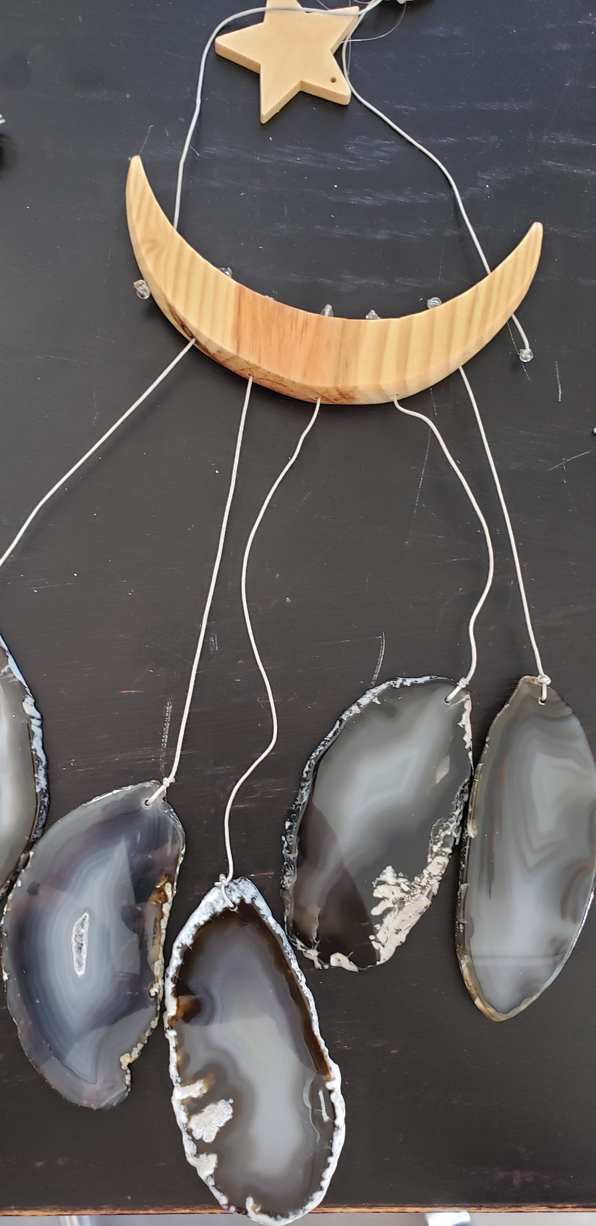 The NEW Star & Crescent Moon Agate Wind Chime features a mesmerizing wood crescent moon embellished with vibrant stones that mimic natural agate slices, all elegantly accentuated by two wooden triangular shelves.