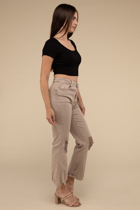 Person wearing acid washed high waist distressed straight pants and beige sandals against a neutral background.