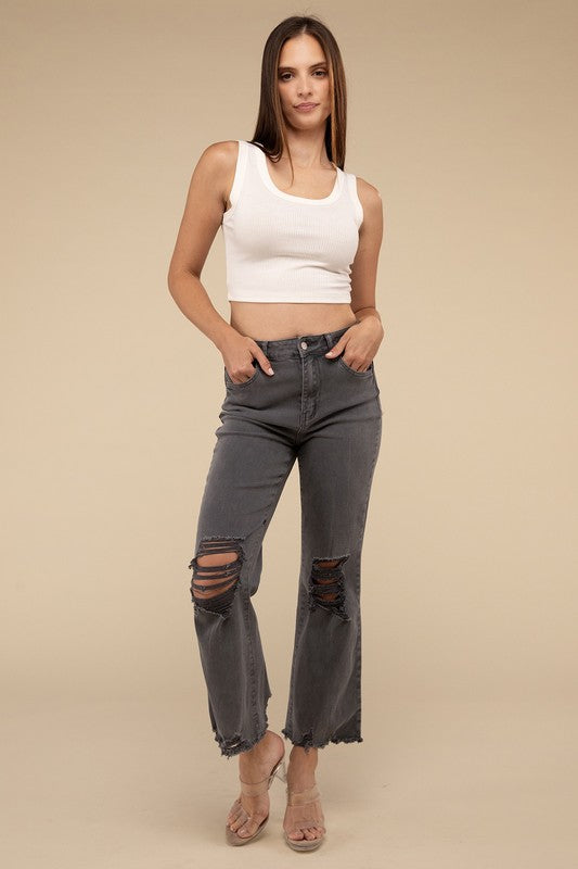 Person wearing acid washed high waist distressed straight pants and beige sandals against a neutral background.