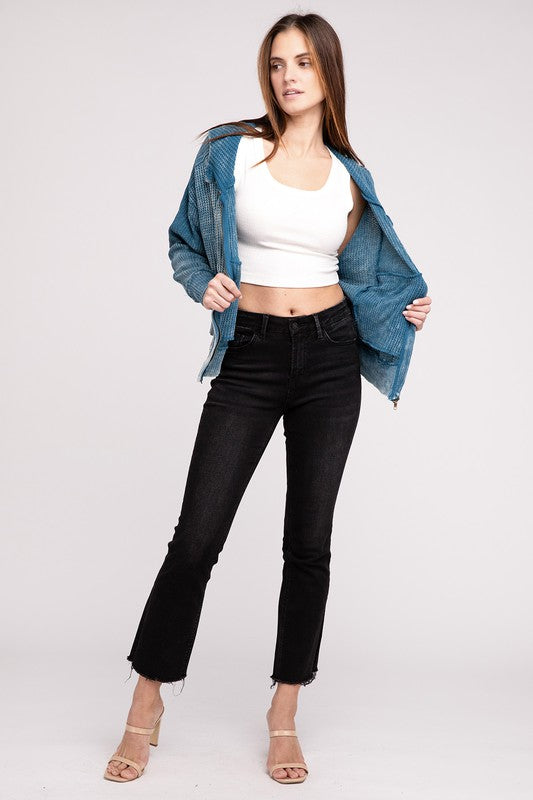 Woman in a Acid Wash Cotton Waffle Hooded Zip-Up Jacket with pockets and black pants, smiling and posing with hands on hips, against a light gray background.