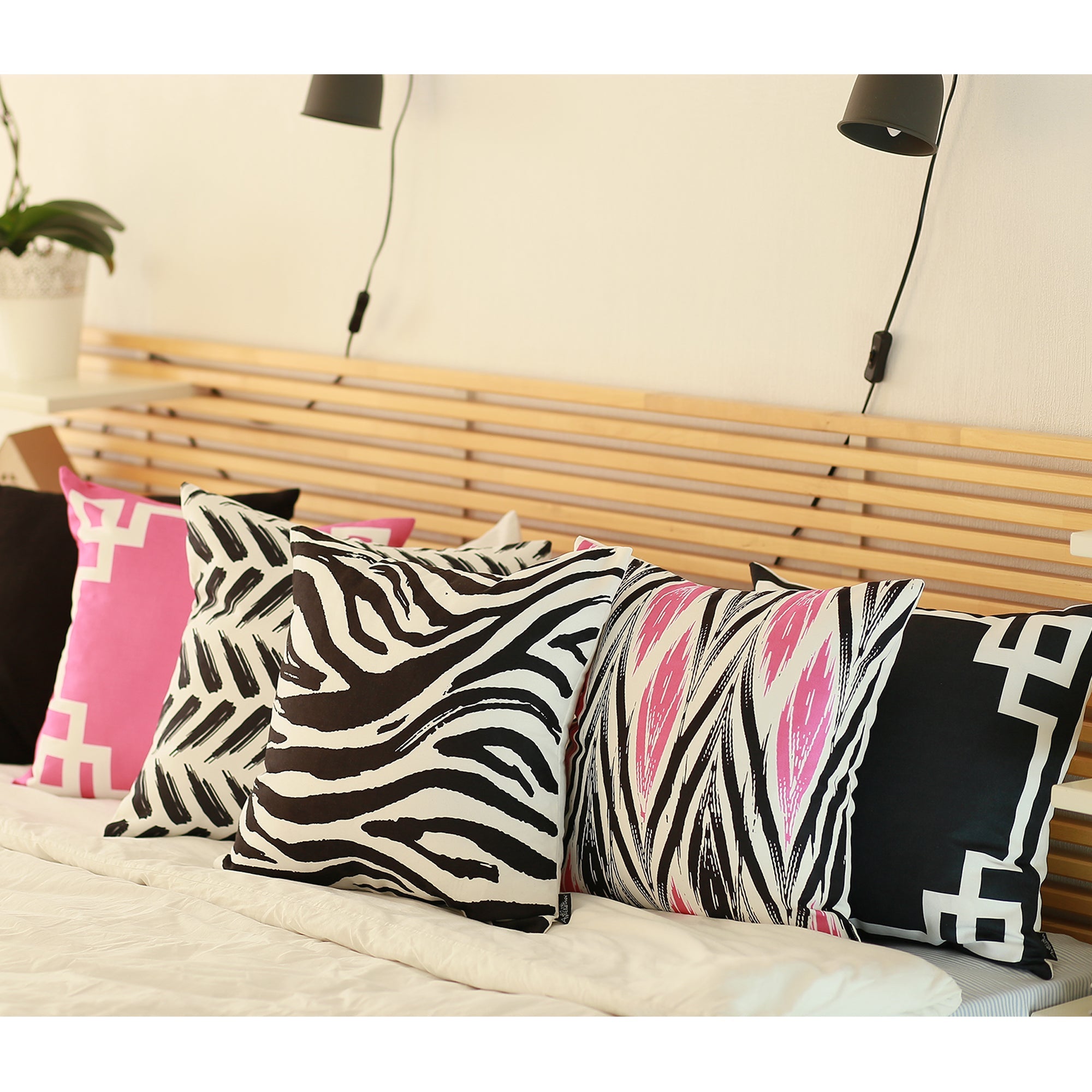 A black wicker chair adorned with a Geometric Pink & White Square 18" Throw Pillow Cover & Insert, crafted from OEKO-TEX certified fabrics and designed with a striking white geometric border.