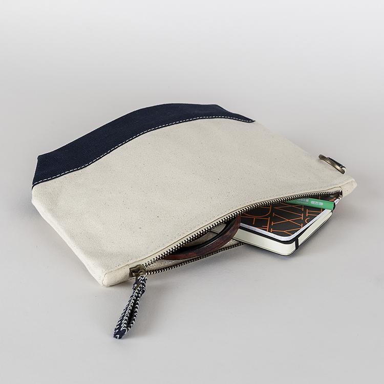 A small heavyweight canvas pouch with a black bottom, featuring a sturdy metal zipper and side loop detail, from the All In Zip Top Pouch collection.