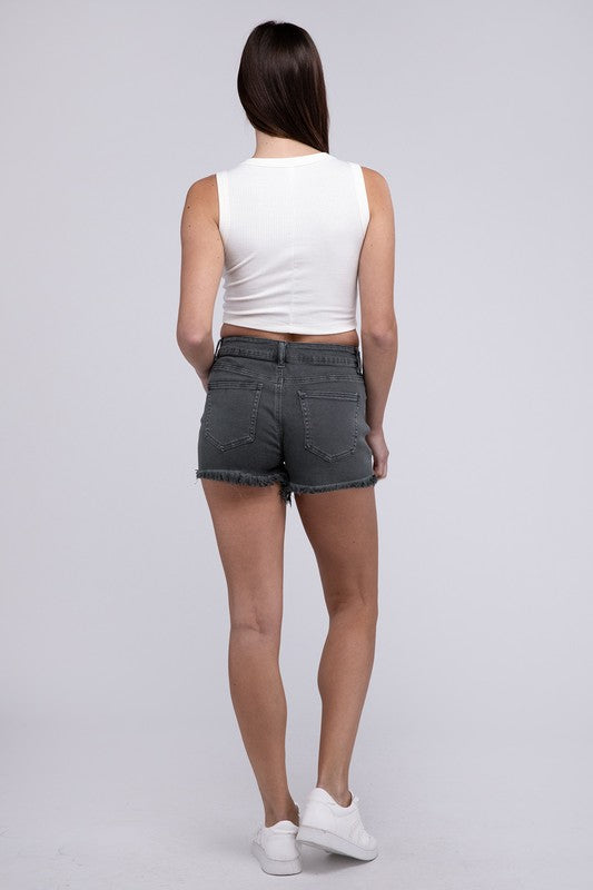 Close-up of a person wearing Acid Washed Frayed Cutoff Hem Shorts and a black top with lace-up details on the side.