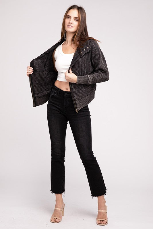 Woman in a Acid Wash Cotton Waffle Hooded Zip-Up Jacket with pockets and black pants, smiling and posing with hands on hips, against a light gray background.