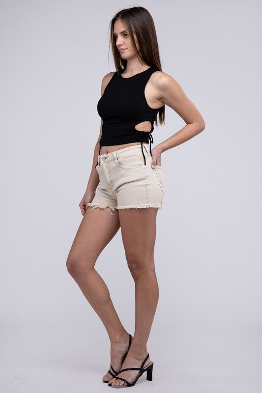 Close-up of a person wearing Acid Washed Frayed Cutoff Hem Shorts and a black top with lace-up details on the side.