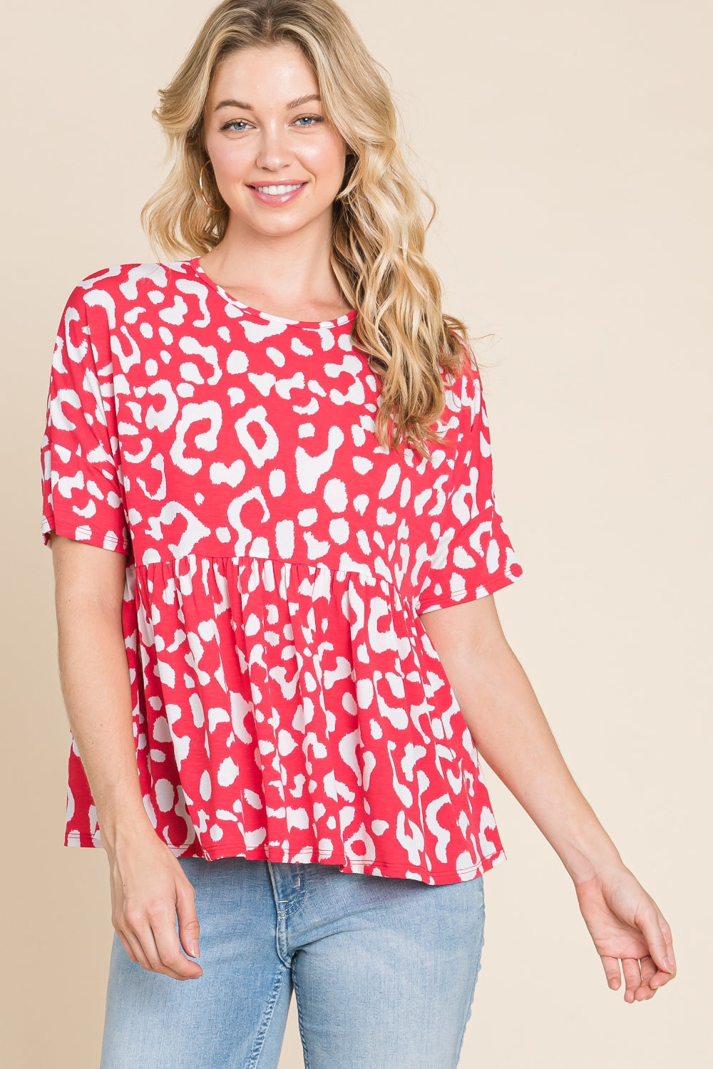 A person in a red and white BOMBOM Leopard Peplum Babydoll Blouse and blue jeans stands against a beige background.