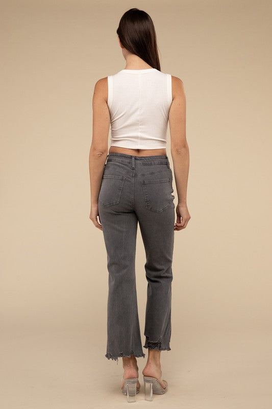 Person wearing acid washed high waist distressed straight pants and beige sandals against a neutral background.