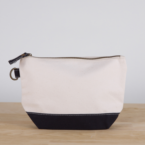 A small heavyweight canvas pouch with a black bottom, featuring a sturdy metal zipper and side loop detail, from the All In Zip Top Pouch collection.