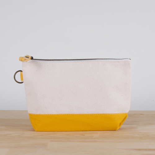 A small heavyweight canvas pouch with a black bottom, featuring a sturdy metal zipper and side loop detail, from the All In Zip Top Pouch collection.