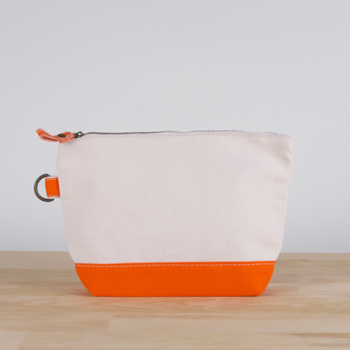 A small heavyweight canvas pouch with a black bottom, featuring a sturdy metal zipper and side loop detail, from the All In Zip Top Pouch collection.