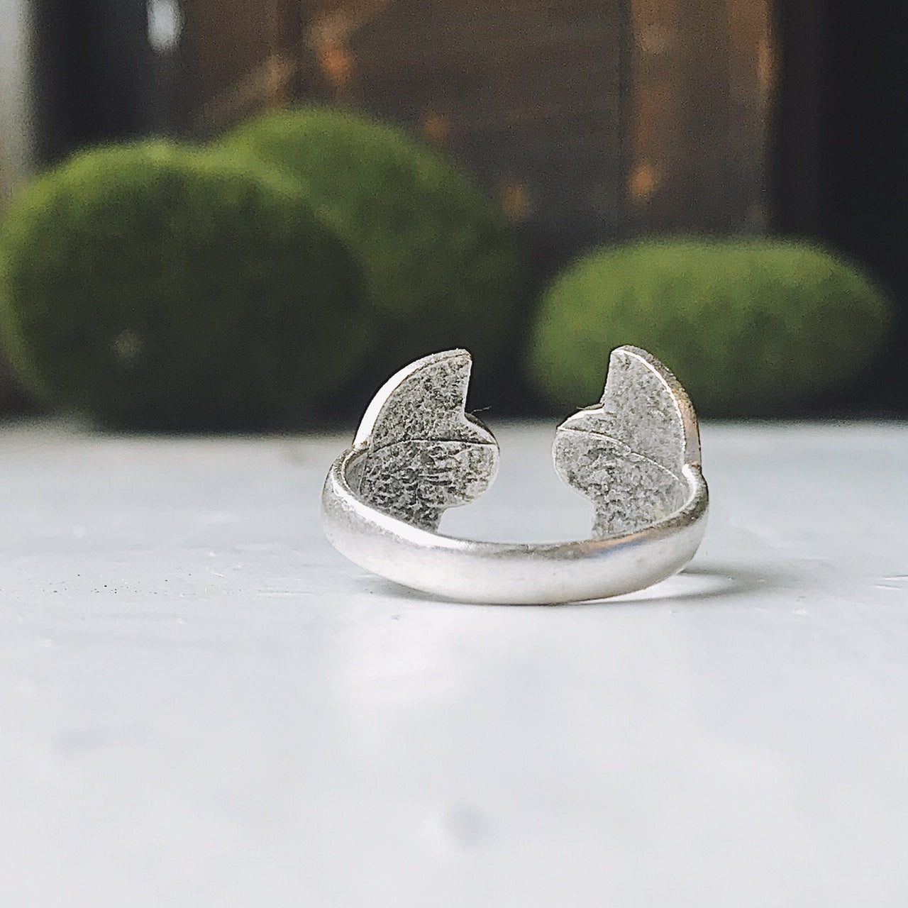 Two artistic rings are displayed on a white surface, one exuding bohemian charm with its gold band and captivating copper turquoise stone, while the other showcases a silver band paired with a dark purple stone. Both pieces from the "Dawn to Dusk - Two Stone Turquoise Boho Sunburst Ring" collection radiate galaxy flair and offer the convenience of an adjustable design.