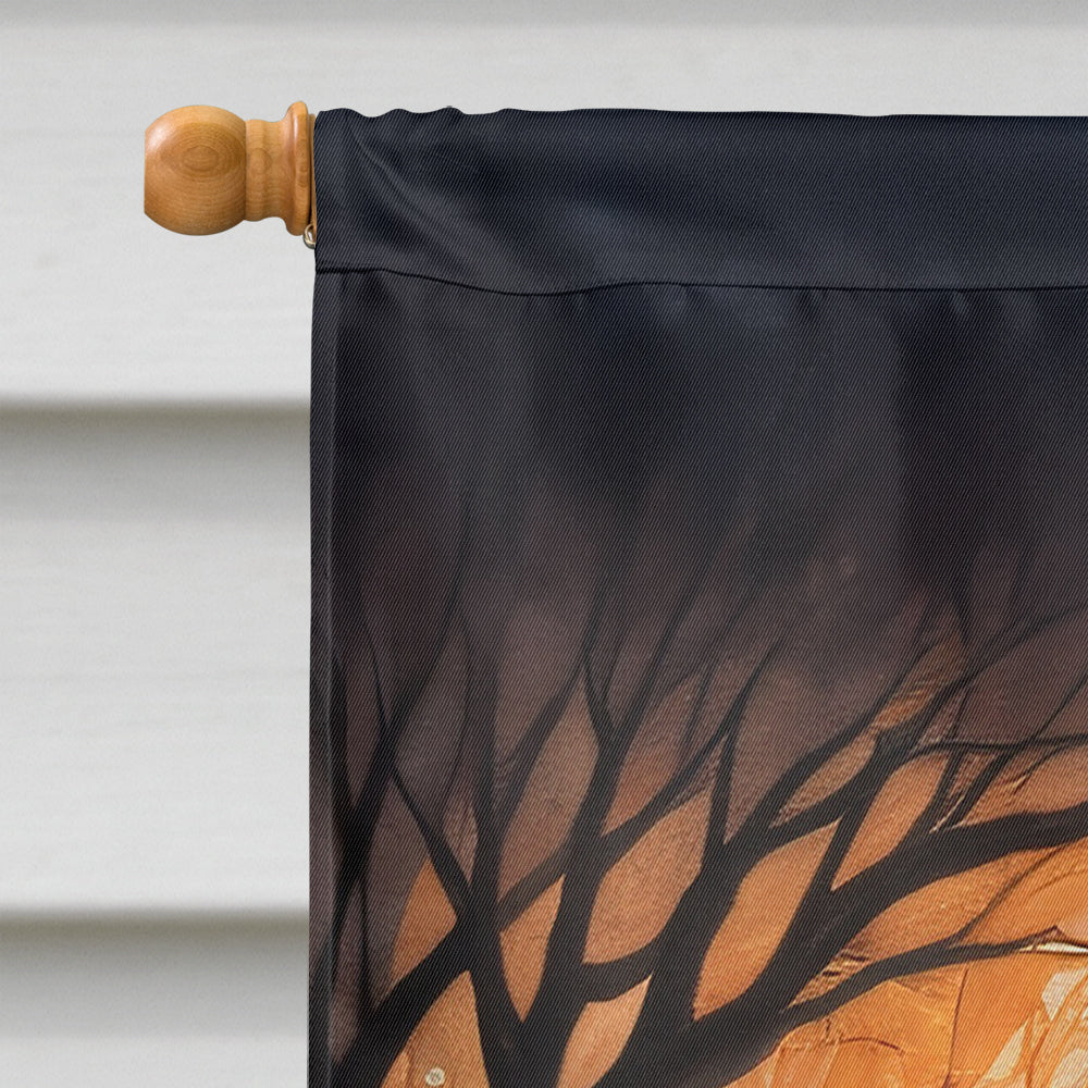 A Chocolate Labrador Retriever sits in a cemetery surrounded by carved pumpkins with glowing faces. Tombstones and bare trees loom in the background, while a Spooky Halloween House Flag featuring the dog waves gently, enhancing the spooky atmosphere.