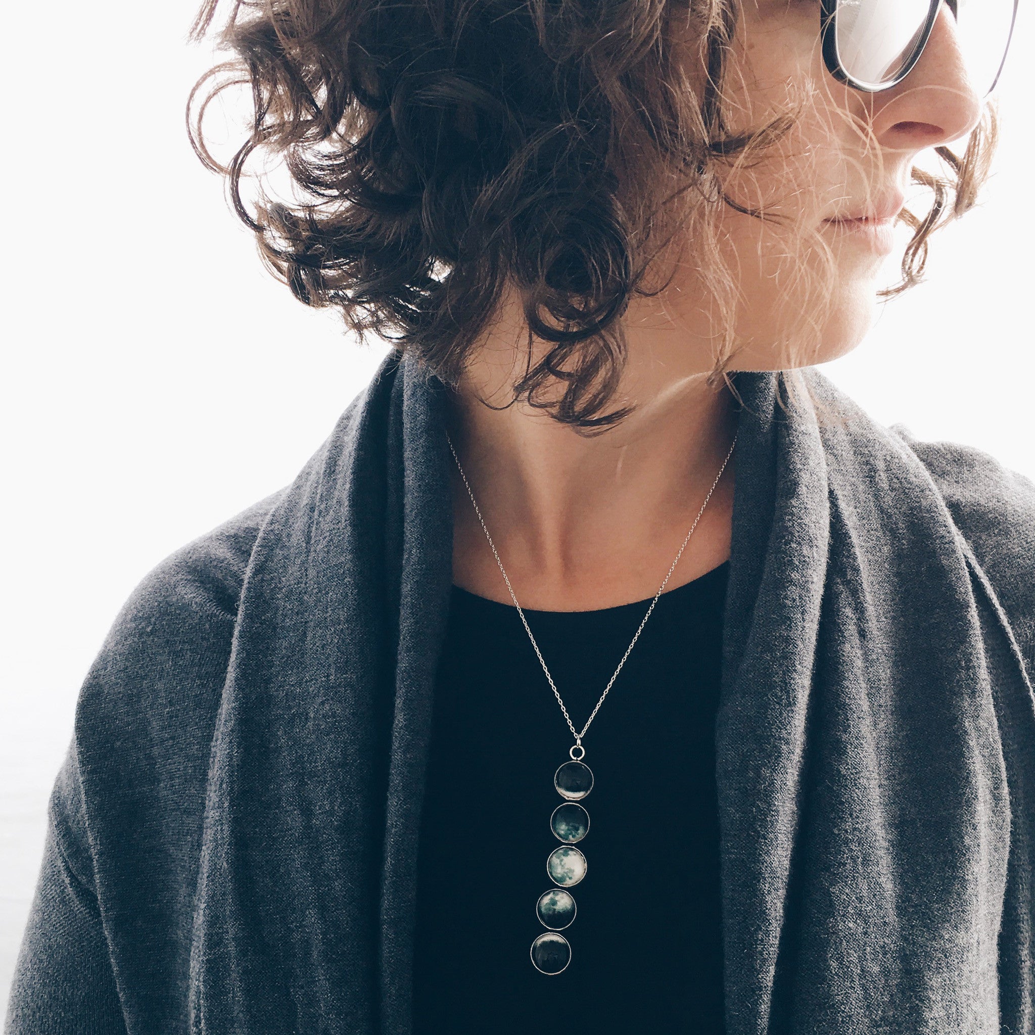 Introducing the Moon Phase Pendant Necklace: a breathtaking piece adorned with five round pendants, each beautifully depicting the phases of the moon against a starry background, capturing the splendor of the lunar cycle.