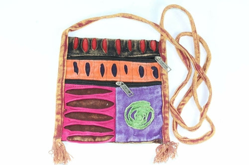 The Spiral Cross Body Patchwork Passport Bag features a vibrant hippie style with red, purple, blue, and green patterns. Handmade from cotton, it comes with multiple zippers and an adjustable strap, adorned with a charming flower design on the lower right corner.