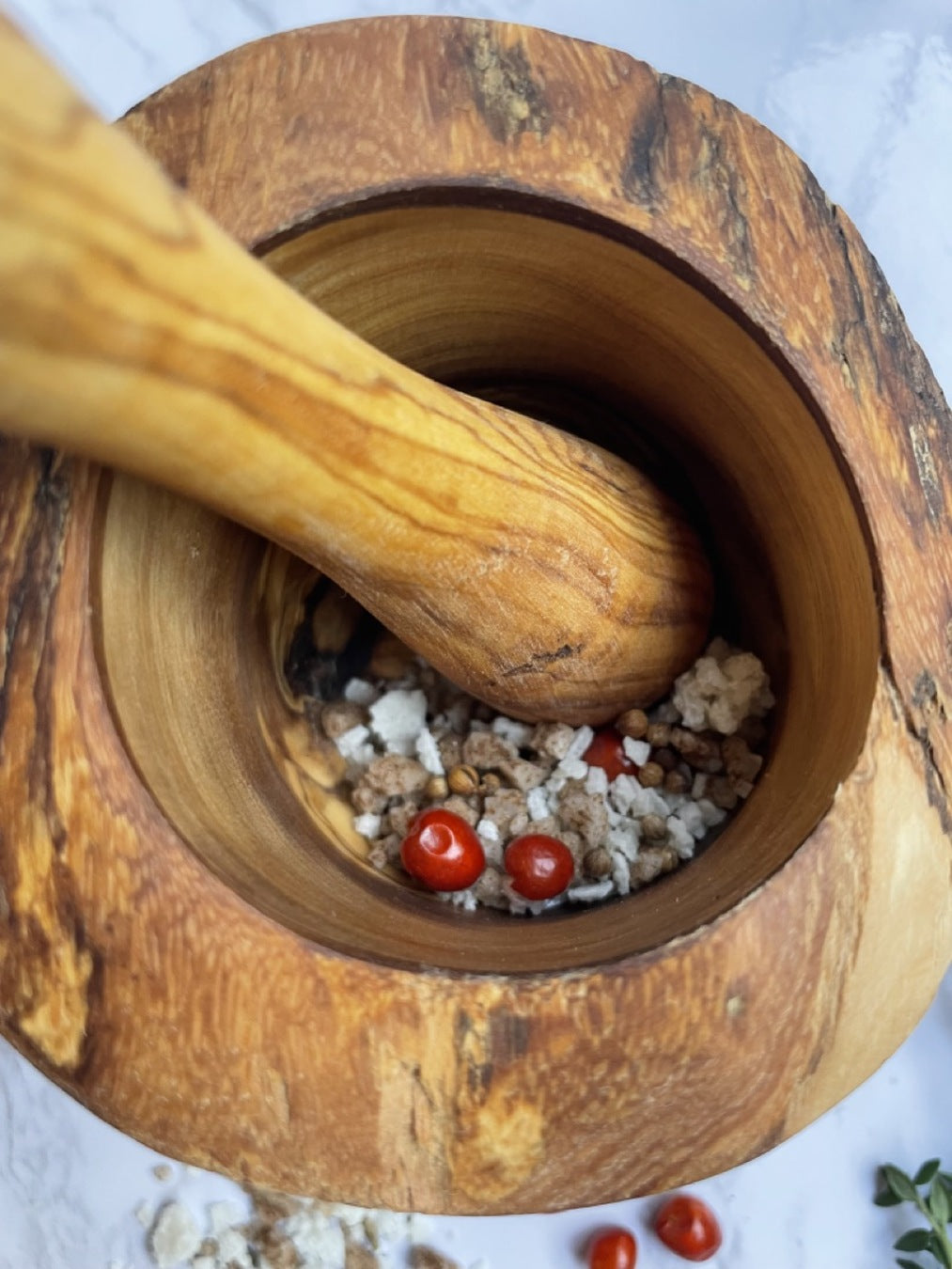 The Olive Wood Rustic Mortar and Pestle, featuring a smooth, polished surface and striking grain patterns, stands out as a sturdy kitchen accessory against a plain white background.