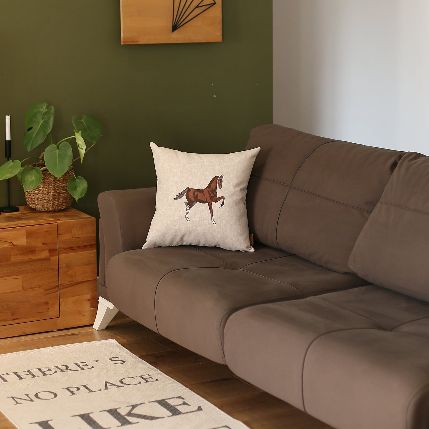 Placed on a brown sofa is the Boho Embroidered Horse Throw Pillow, a solid beige and brown square cushion measuring 18" x 18", featuring an illustration of a horse and made with recycled polyester filling, ensuring OEKO-TEX certification.