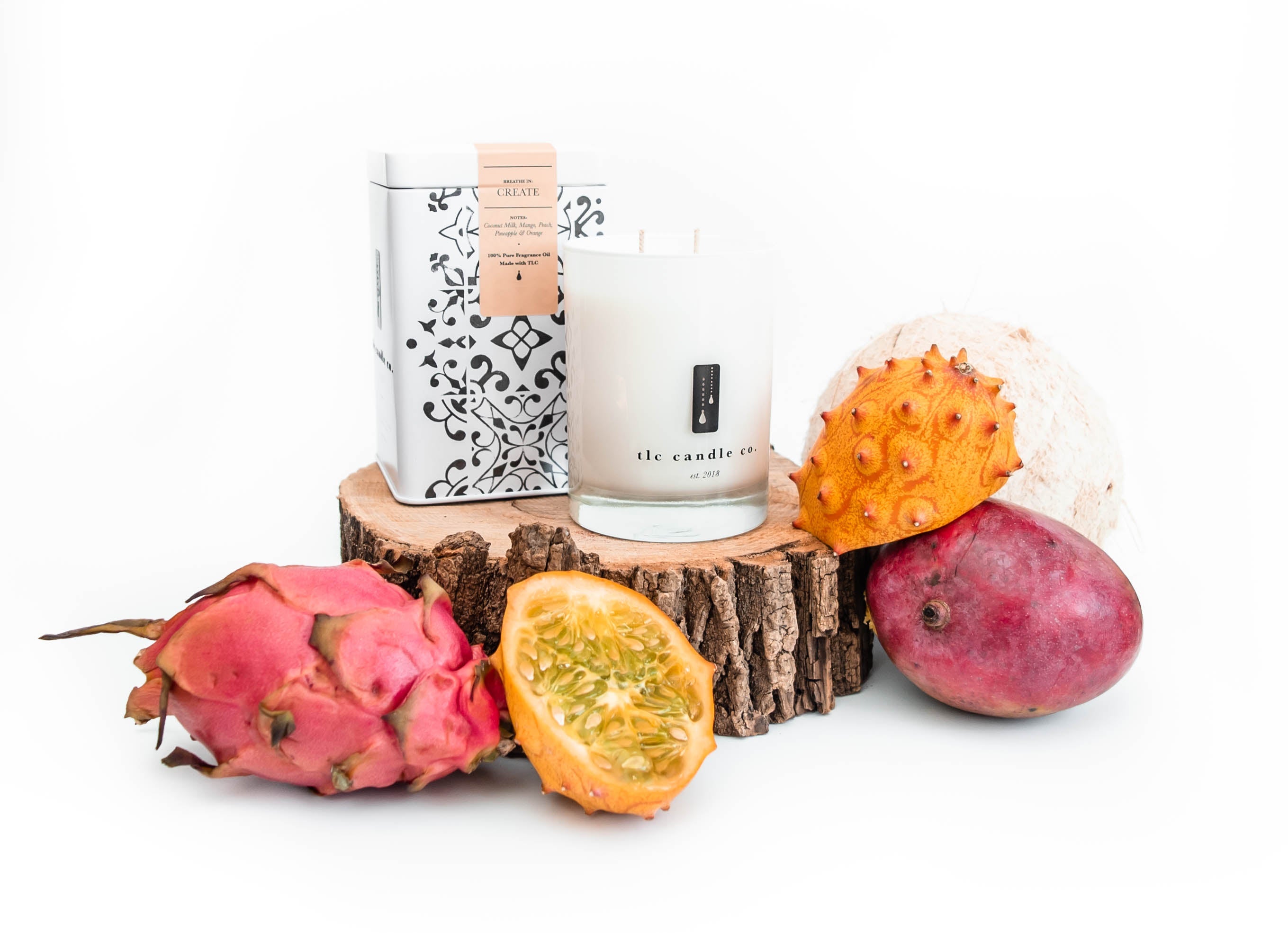 A display featuring the Create - Coconut and Tropical Fruits Soy Candle and a tea tin, all set against a white background.