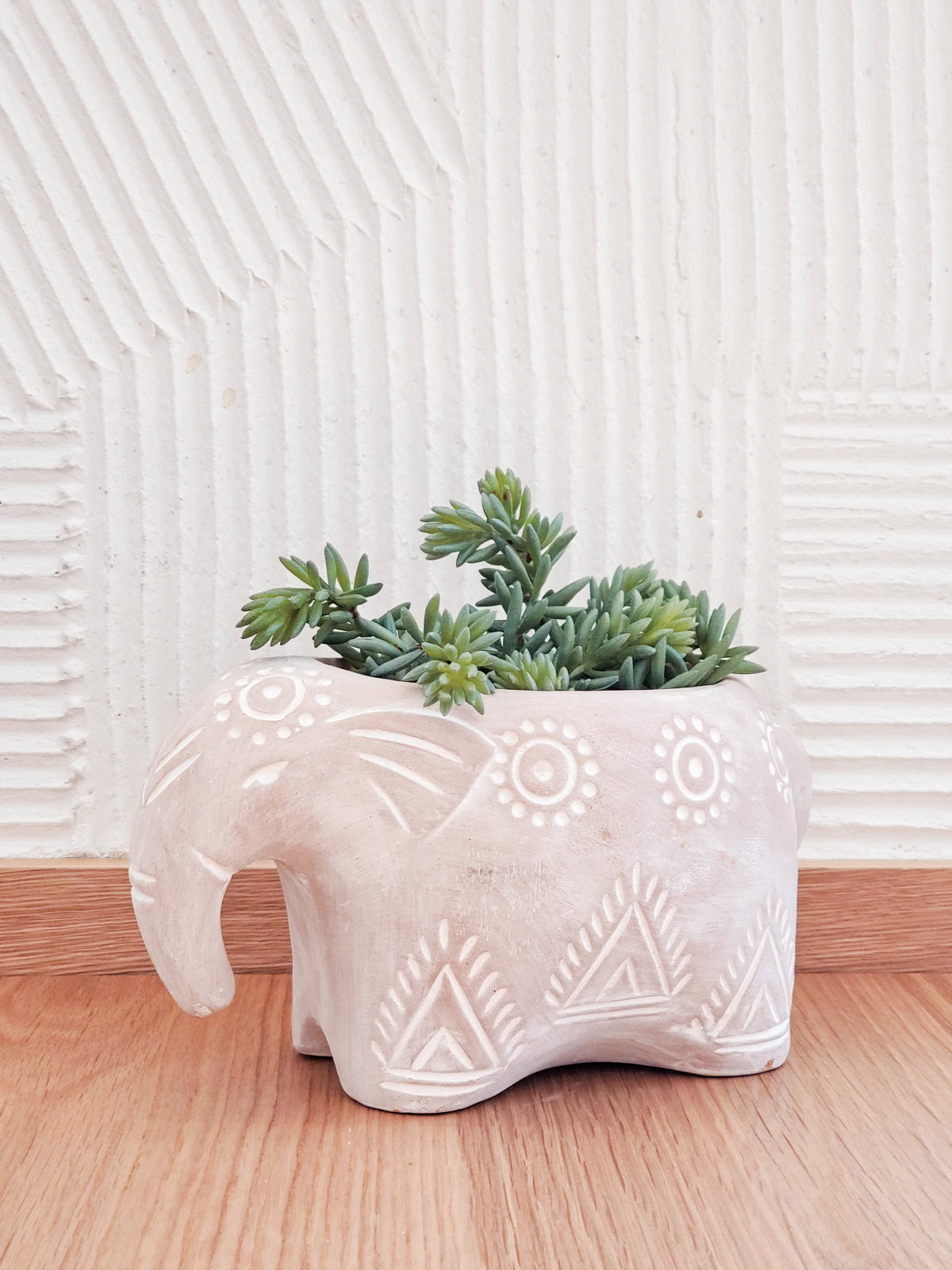 Introducing the Terracotta Pot - Folk Elephant, a captivating decorative planter crafted by Fair Trade artisans. This elephant-shaped piece showcases painted white geometric patterns on a plain background, making it an ideal choice for garden planters and adding an artistic charm to any space with its delightful animal-themed design.
