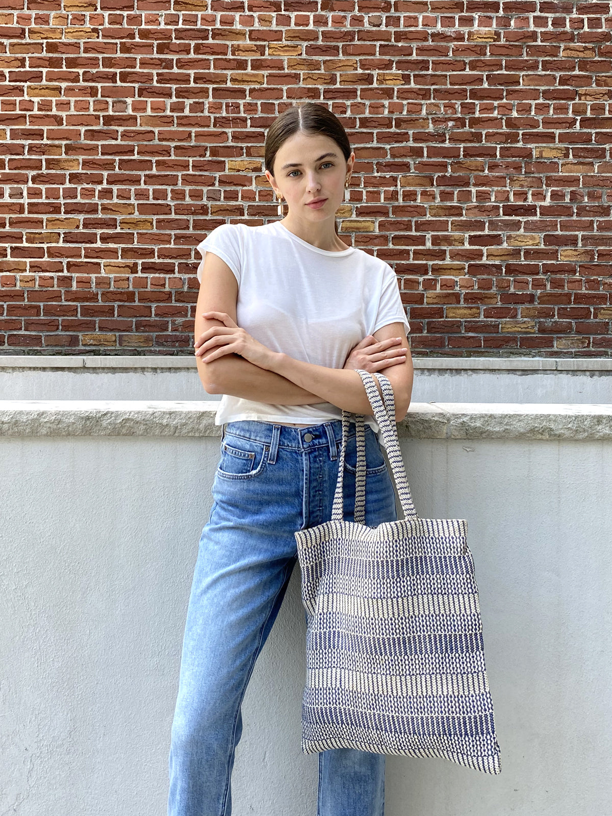 The Dobi Daily Bag - Blue is a tote bag crafted from handwoven jute-cotton fabric by Fair Trade artisans, featuring two handles set against a plain background, with gray and white horizontal stripes.