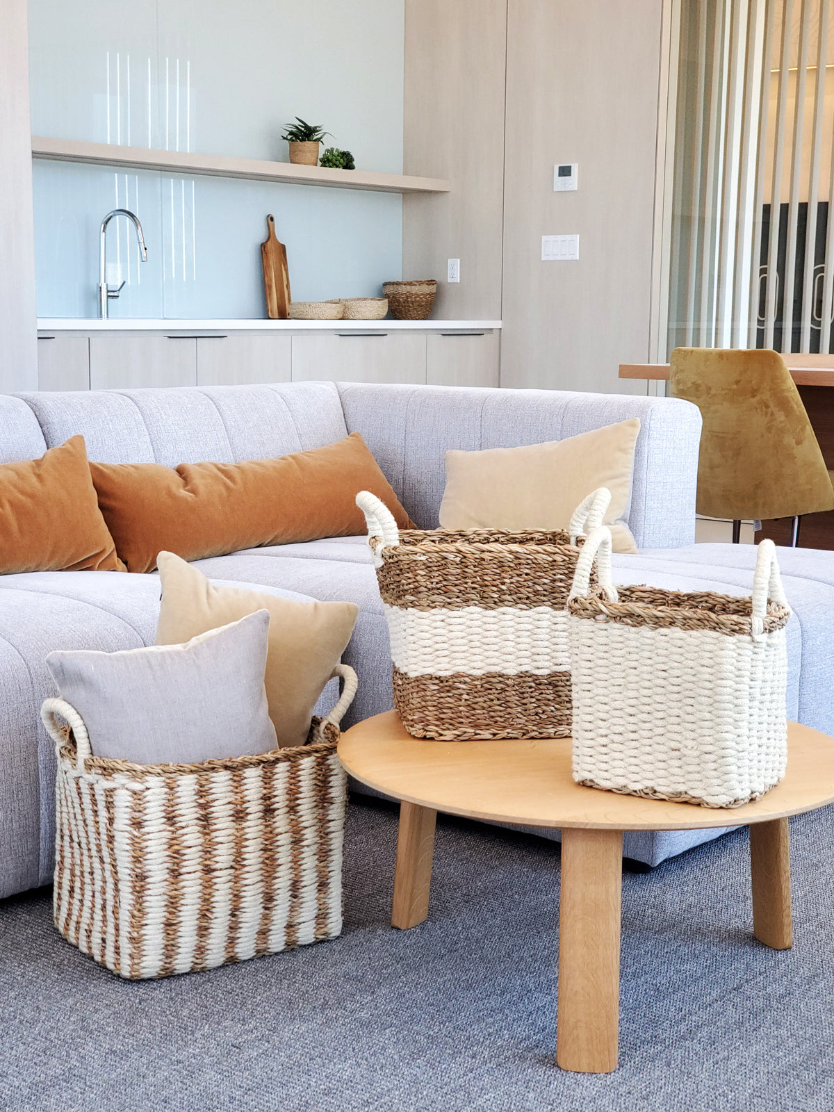 The Ula Storage Baskets, a set of three handmade options with handles in different sizes, are arranged in a row against a plain background. Made from jute wool, these Fair Trade baskets highlight artisanal craftsmanship and sustainable design.