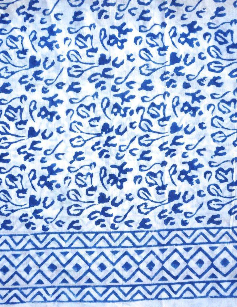 Person wearing an Abstract Blue Sarong and beige heels, standing against a textured white wall.