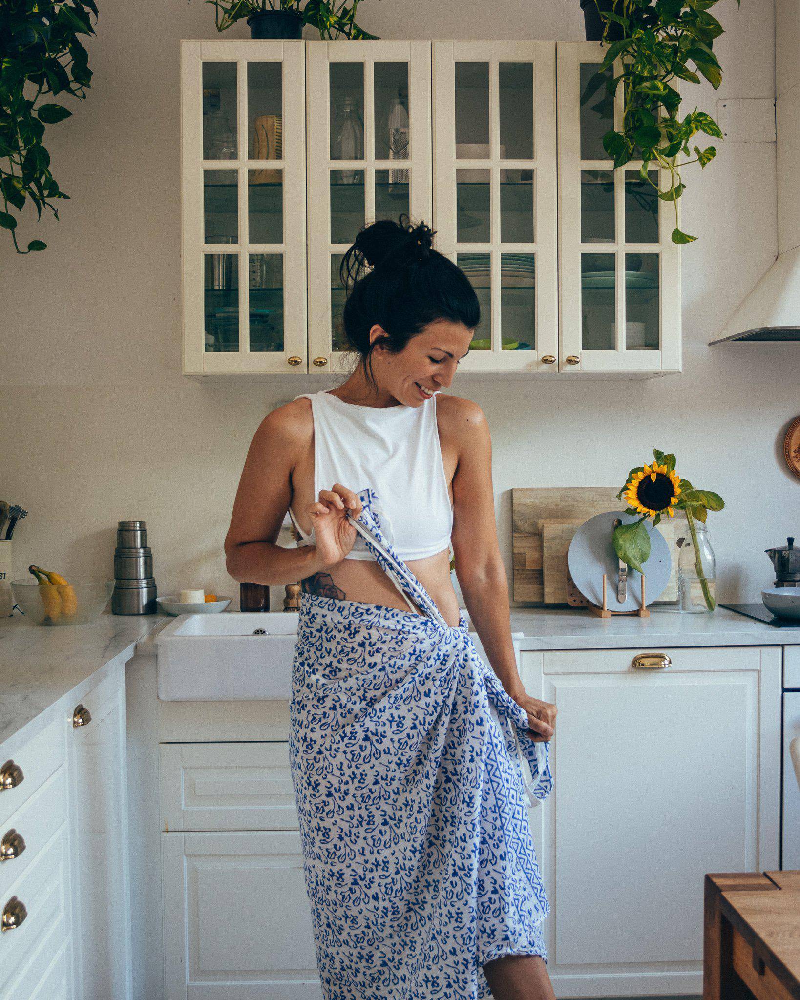Person wearing an Abstract Blue Sarong and beige heels, standing against a textured white wall.