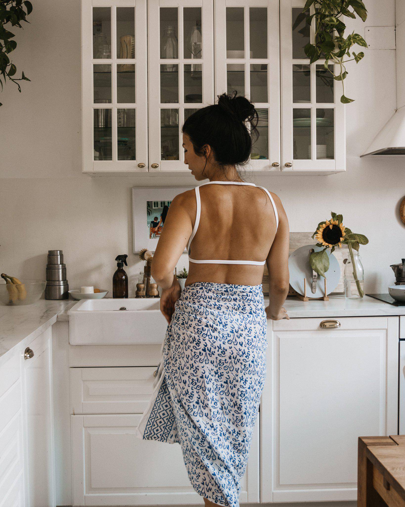 Person wearing an Abstract Blue Sarong and beige heels, standing against a textured white wall.