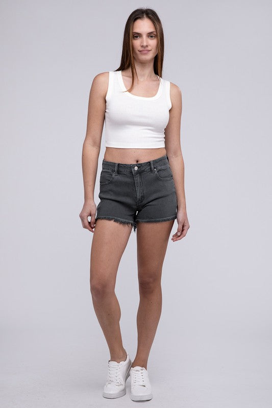 Close-up of a person wearing Acid Washed Frayed Cutoff Hem Shorts and a black top with lace-up details on the side.