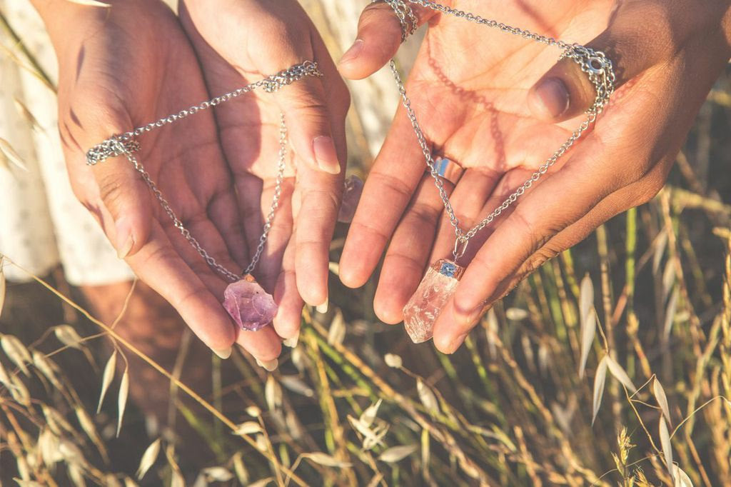 The Raw Quartz Crystal Statement Necklace, adorned with a natural quartz pendant, rests elegantly on a dark wooden surface, symbolizing spiritual growth through its silver chain and clear design.