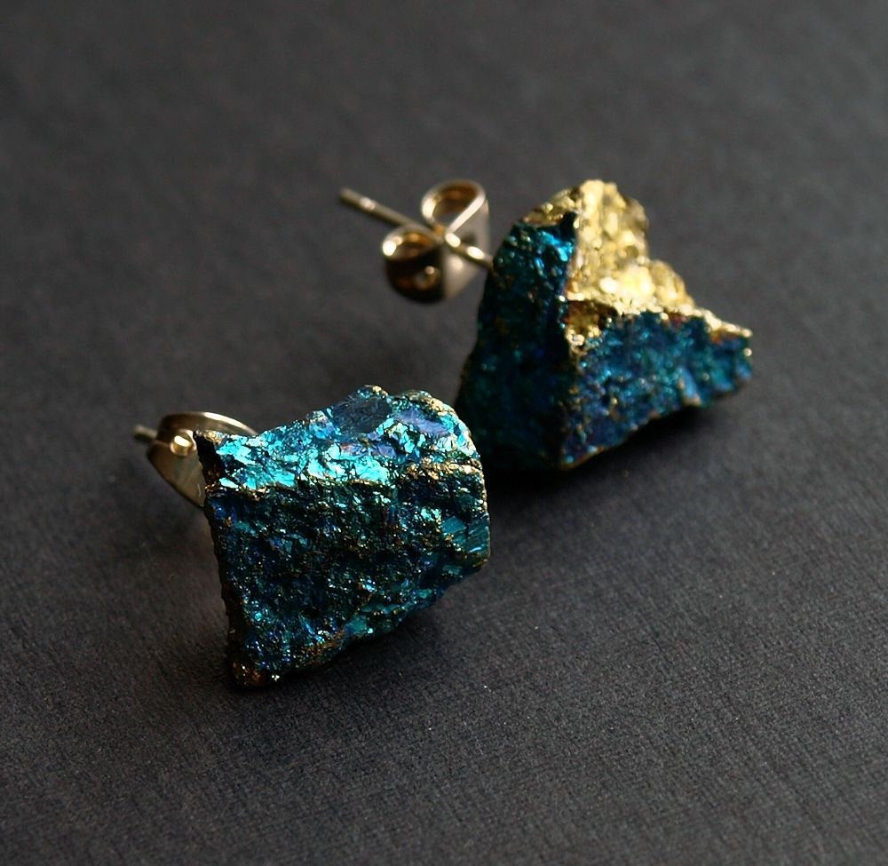 A pair of Raw Peacock Ore Chunk Earrings glisten on a dark surface, making a bold statement in unique jewelry design.