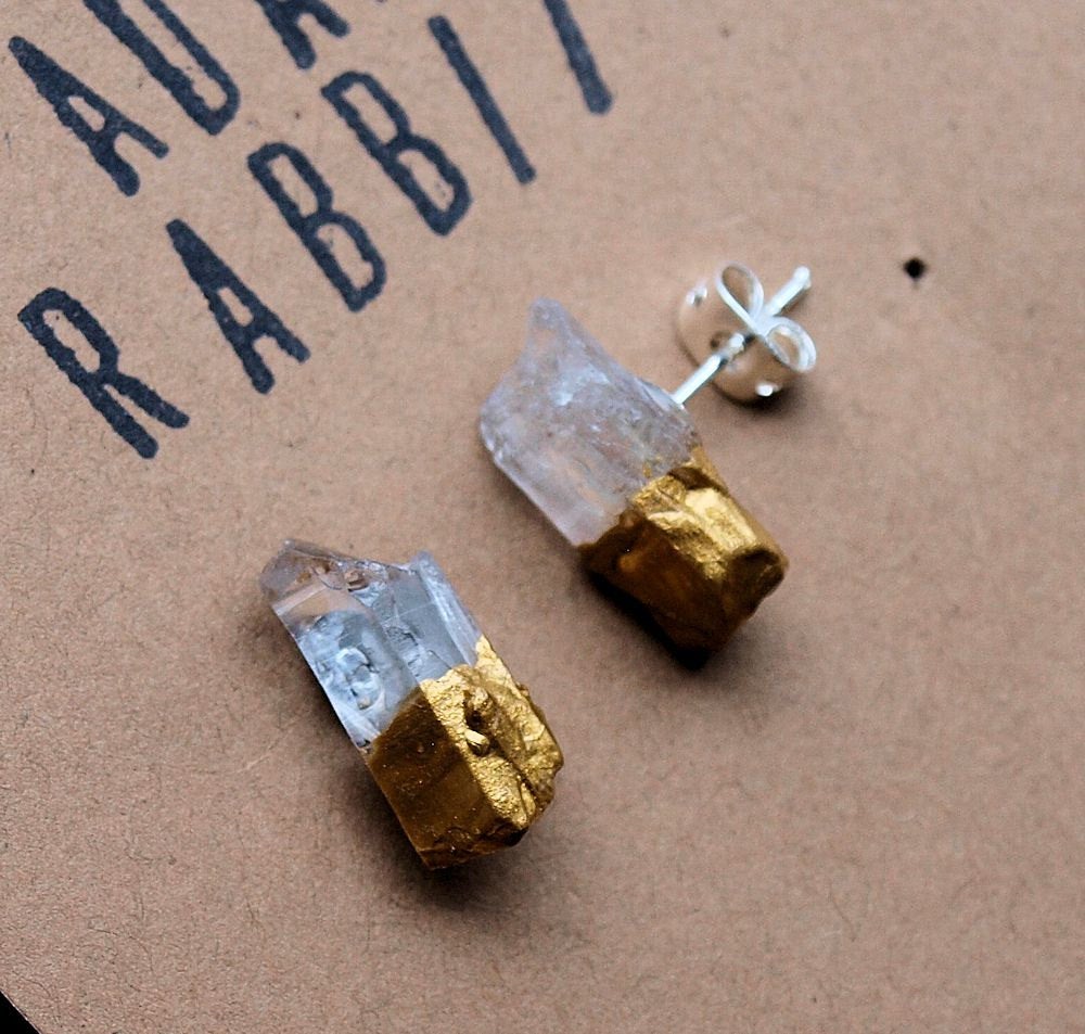 The Gold & Raw Quartz Chunk Earrings, showcasing their raw beauty with gold accents, stand out on a gray backdrop, making a bold statement in the realm of unique jewelry.