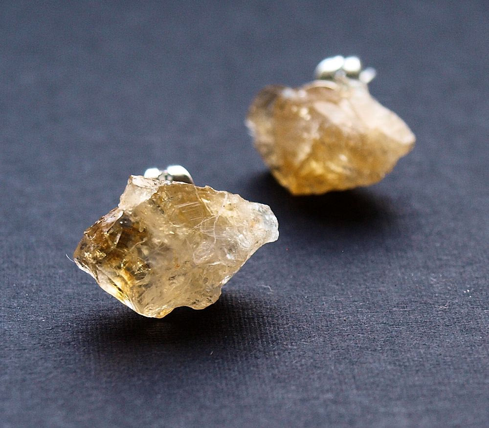 A pair of Raw Citrine Chunk Earrings, also known as Geo Earrings or Rock Stud Earrings, are elegantly showcased on a dark background, highlighting the allure of unique crystal jewelry.