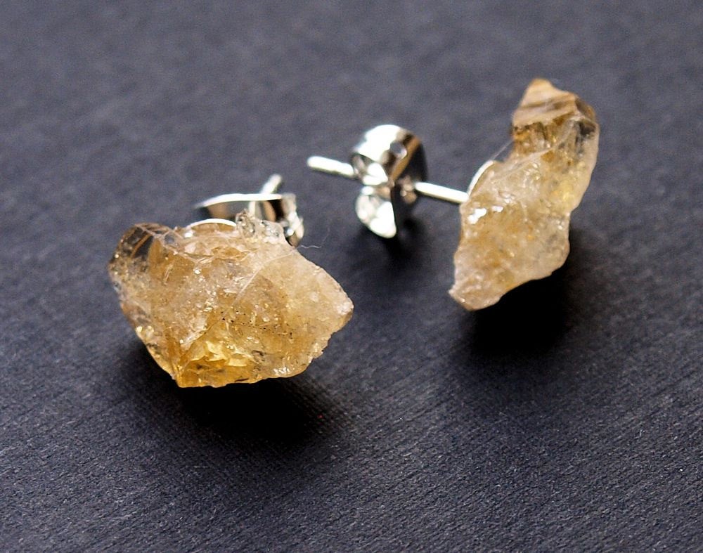 A pair of Raw Citrine Chunk Earrings, also known as Geo Earrings or Rock Stud Earrings, are elegantly showcased on a dark background, highlighting the allure of unique crystal jewelry.