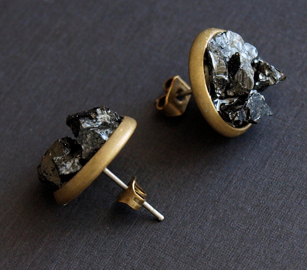 Black Tourmaline Cluster Stud Earrings, designed with raw black tourmaline stones encased in circular gold frames against a dark backdrop, offer protection jewelry that exudes both elegance and tranquility.