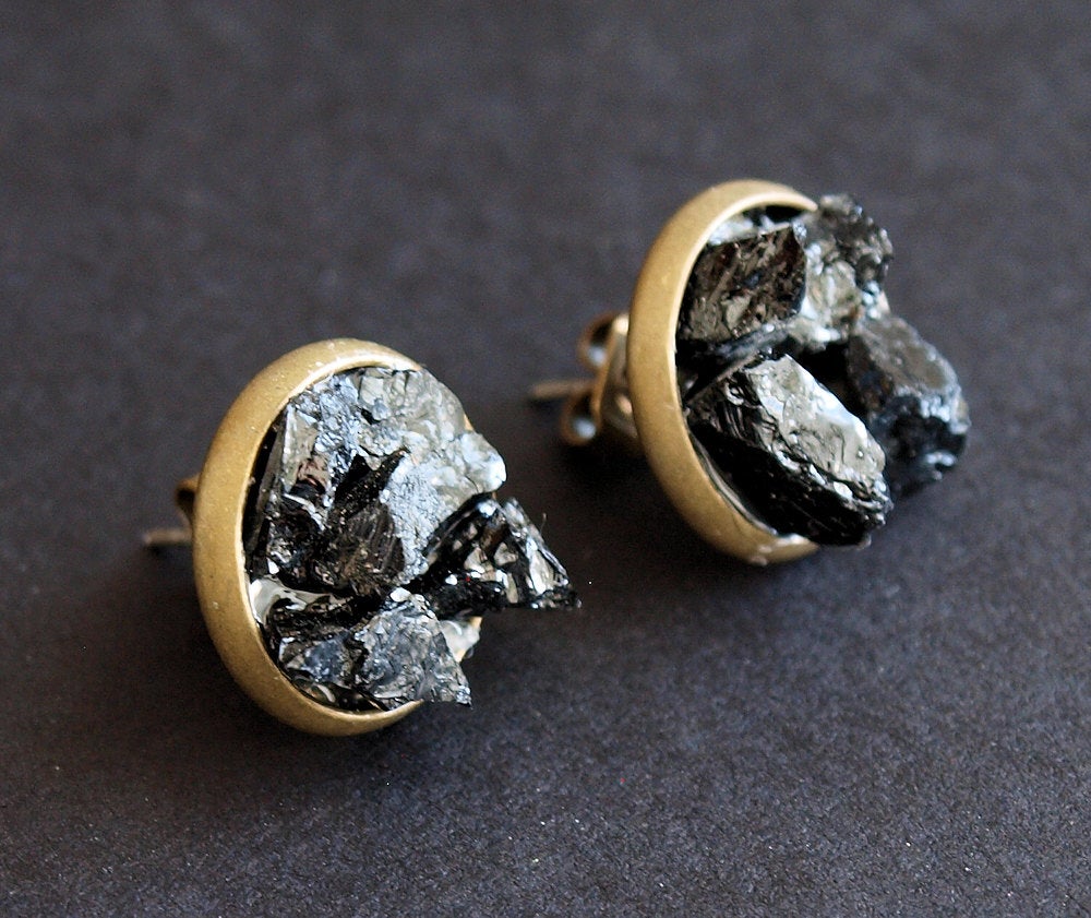 Black Tourmaline Cluster Stud Earrings, designed with raw black tourmaline stones encased in circular gold frames against a dark backdrop, offer protection jewelry that exudes both elegance and tranquility.