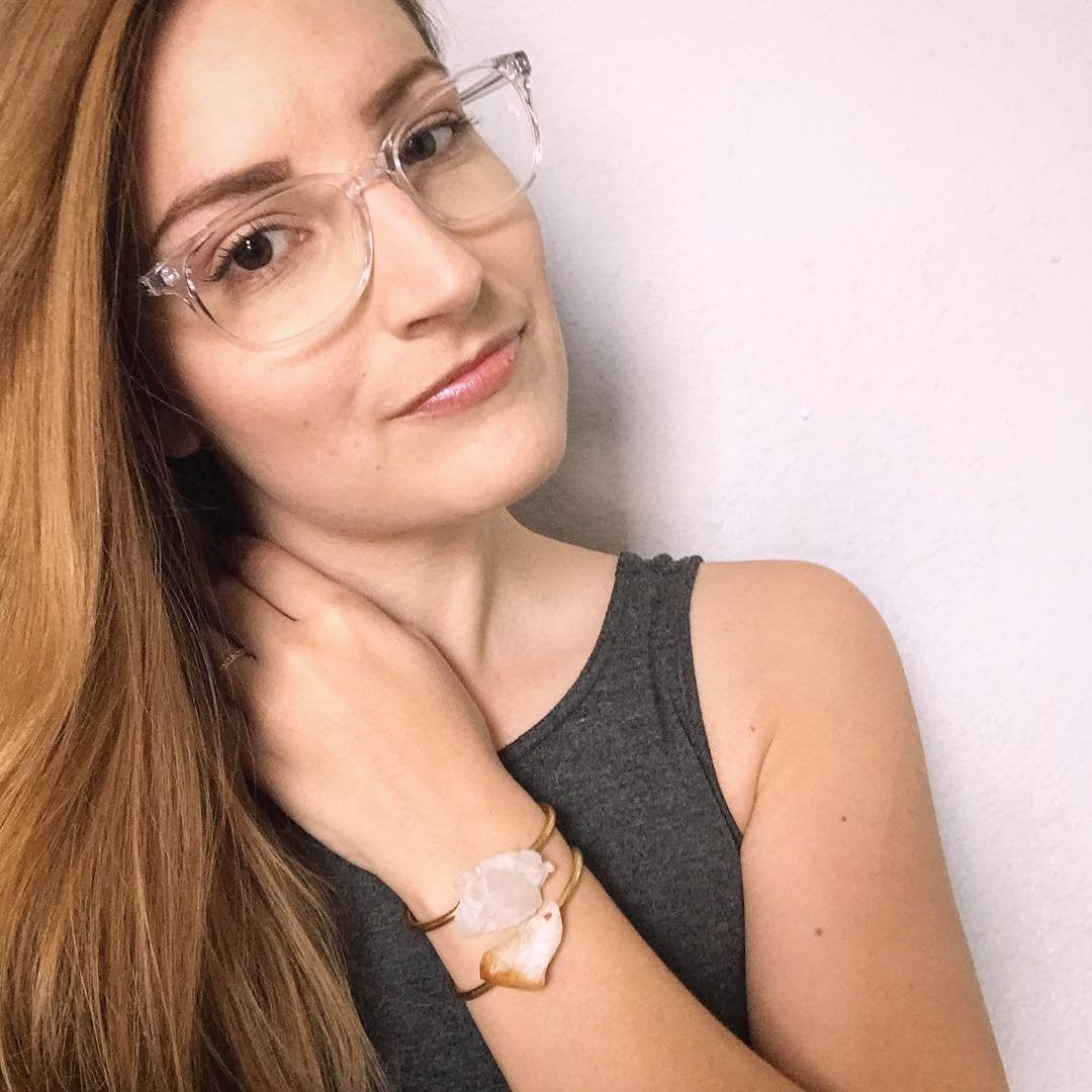 The Raw Citrine Bangle features a stunning large raw crystal centerpiece set against a dark background in an adjustable brass band.